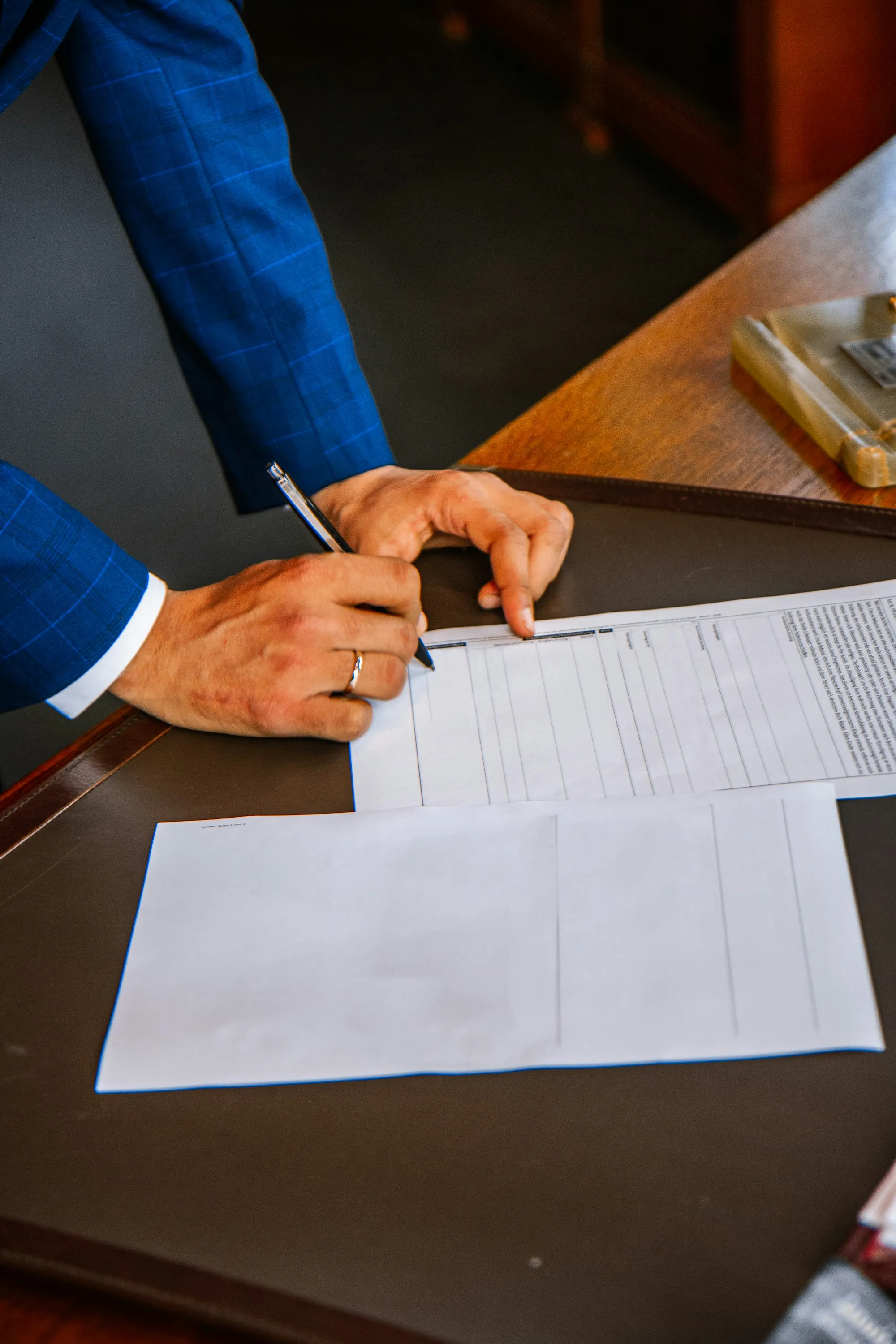 A hand filling in a printed form at a desk