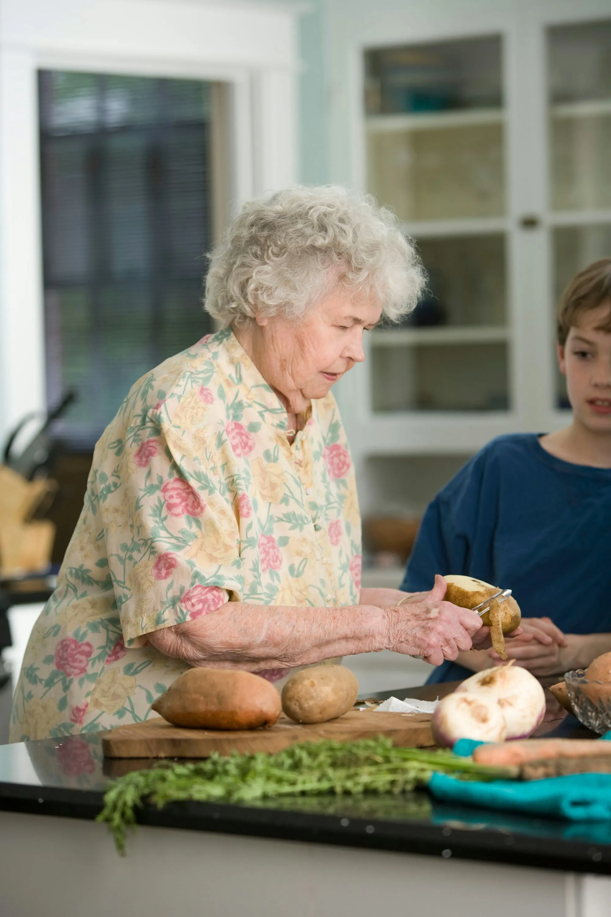 An older woman and a visitor preparing food together